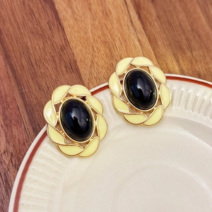 Detailed macro shot of vintage oval pearl earrings with gold base and black enamel inlay