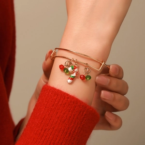 Close-up of a Christmas adjustable gold bracelet with candy cane charm on a wrist