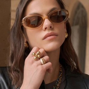 Close-up of golden floral rings and beaded jewelry with elegant sunglasses