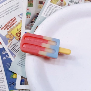 Close-up of colorful popsicle-shaped hair clips in red and blue on vintage newspapers