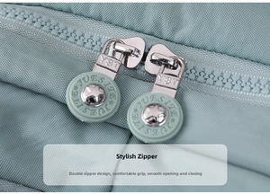 Detail of dual silver metal zippers and green round star pulls on nylon backpack