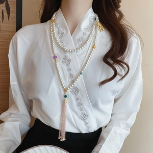 Detail of layered pearl body chain with lotus gold accents and pink fringe tassel
