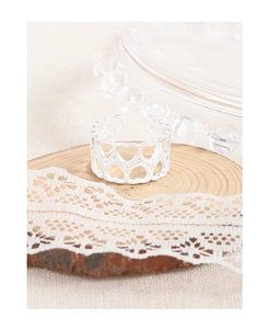 Close-up of silver hollow heart ring on a wooden stand with white lace decorative elements