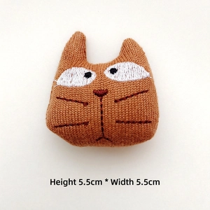 Detail of caramel crochet cat badge showing 5.5cm size and hand-knitted texture