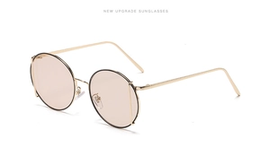 Detail view of round retro sunglasses with light tea lenses and gold metal frames