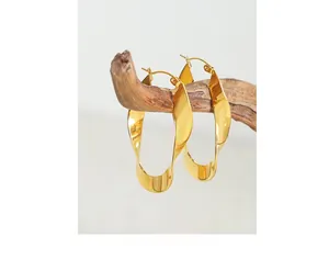 Detail of twisted U-shape gold earrings displayed on a natural wooden branch setup