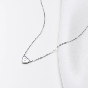 Close-up of heart-shaped pendant engraved with letter Q on a polished silver chain
