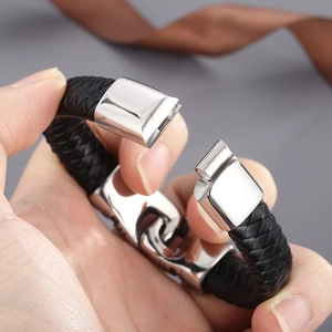 Braided black leather bracelet for men with silver magnetic clasp shown held in hand