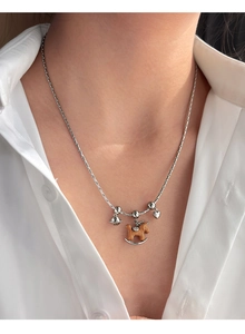 Gros plan d'un collier en argent avec pendentif cheval à bascule en bois et breloques