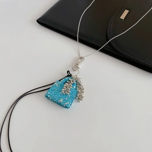 Détail du pendentif sac bleu à paillettes avec des pompons en perles argentées