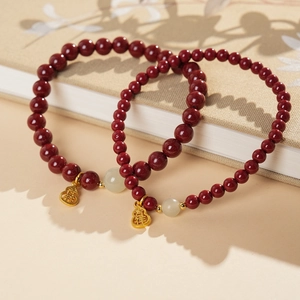 Close-up of red cinnabar beads bracelet with golden fu pendant and white nephrite jade