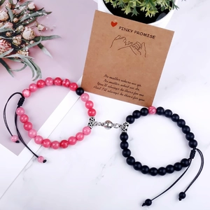 Detail of pink and black natural stone magnet heart bracelets on a pinky promise card