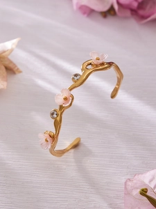 Macro shot of 18k gold plated floral bangle featuring pink enamel flowers and 5A zircon stones