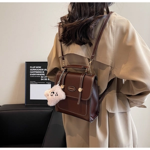 Detail view of vintage dark brown leather backpack with double straps and plush pendant