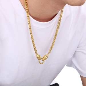 Close-up of golden hip hop chain with dual skull heads and central ring on model
