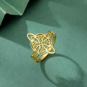 Macro shot of gold Celtic knot stainless steel ring on textured green background
