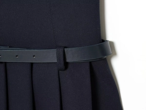 Detail eines dunkelblauen Kleides mit passendem Gürtel und Faltenrock aus Twill-Stoff