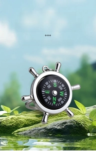 Macro detail of nautical helm compass keychain on a mossy rock in nature setting