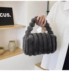 Detail of dark grey faux fur handbag showing unique pleated texture and pompom ball handle
