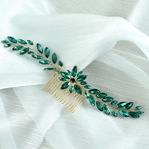 Detail showing bridal hair comb with gold-tone leaf design and emerald green rhinestones