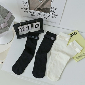 Close-up of black and cream mid-calf socks with sweet bow details in a lifestyle setting