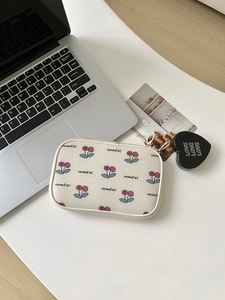 Macro shot of rectangular cherry print makeup bag with a heart tag and zipper
