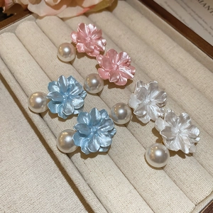 Detail of three pairs of resin flower earrings with pearls in pink blue and white