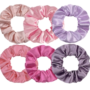 Detailed view of six premium satin silk scrunchies in vibrant pink and purple tones