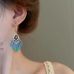 Detail of bohemian tassel bead earrings with blue beads on silver alloy worn by model