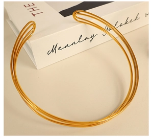 Detailed view of a triple-layer gold choker with C-shape opening on a white book base