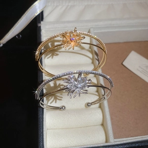 Detail of gold and silver open bangles with zircon starburst design in a jewelry box