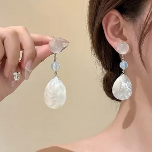 Detail view of the elegant pearl shell pendant earrings with light blue beads on a hook
