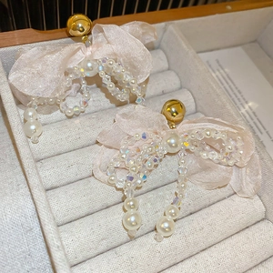 Close-up of pink fabric bow earrings with pearls and crystals on a velvet jewelry tray