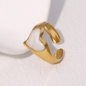 Polierter goldener Herzring mit weißem Stein auf einem schlichten Steinsockel
