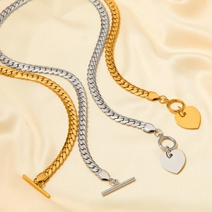 Detail view of gold and silver snake chain necklaces with heart clasp on silk fabric