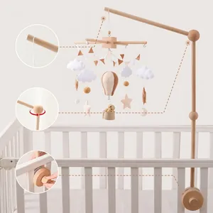 Wooden baby mobile arm with fabric hot air balloons and animals on a white crib