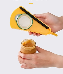 Détail d'un ouvre-bocal en V jaune avec poignée en caoutchouc ouvrant un pot de cacahuètes