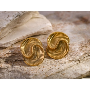 Macro shot of 18k gold stainless steel spiral earrings with radial textures on natural rock