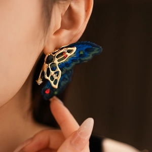 Gros plan détaillé d'une boucle d'oreille papillon vintage avec broderie bleue et cristaux