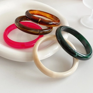 Detailed close-up of a five-piece resin bangle set in diverse tortoise and solid colors