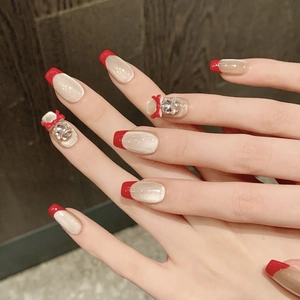 Unghie finte French con fiocchi rossi, base avorio e strass scintillanti