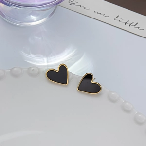 Detail shot of black heart earrings with gold trim on white porcelain dish