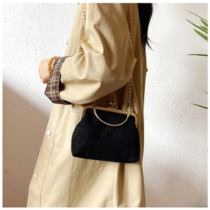 Détail du sac à main en velours noir avec fermoir doré vintage et bandoulière chaîne