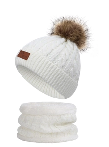 Close-up of white cable knit hat and neck warmer set with a fluffy brown faux fur pompom