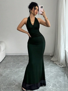 Detail of elegant dark green halter V-neck maxi dress with ruched waist and fishtail hem