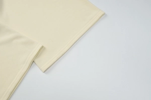 Gros plan du pantalon en maille beige montrant l'ourlet à double couture et la texture