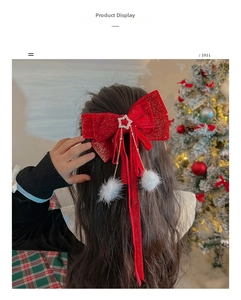 Detail of red velvet bow hair clip with white pom-poms and gold star rhinestones