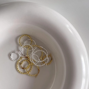 Close-up of gold and silver S925 sterling silver hoop earrings in a ceramic bowl