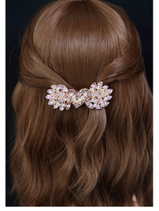 Dettaglio del fermaglio a cuore oro rosa con strass viola sui capelli castani