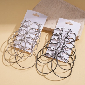 Set of minimalist silver and black hoop earrings in various sizes on a stone display